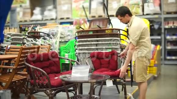 一个成年男子在购物中心的椅子上看他的乡间别墅视频的预览图