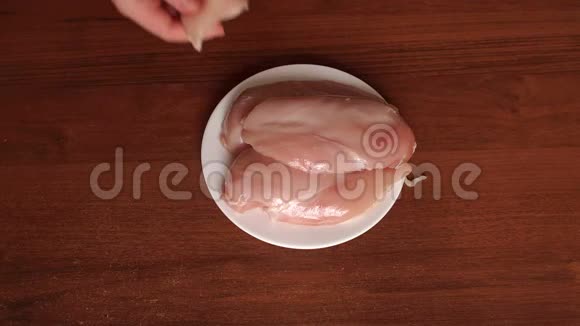 女孩把生鸡肉放在白色盘子里视频的预览图