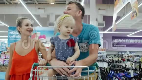 幸福的一家人沿着泰国超市滚动一辆手推车和产品视频的预览图