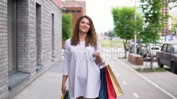一个穿便装的女孩购物后正在街上走慢动作视频的预览图