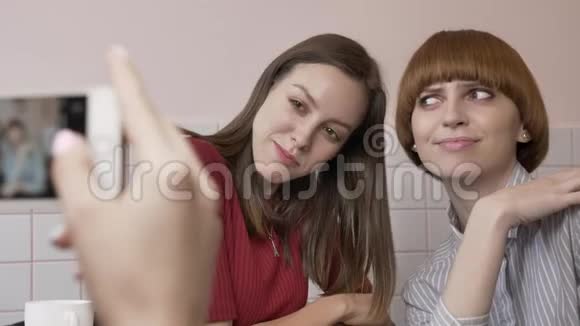 年轻美丽的白种人女孩正在智能手机上拍摄她的两个女朋友坐在咖啡馆里的照片女孩视频的预览图