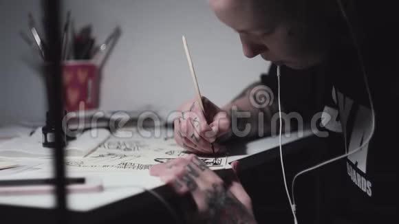 金发纹身艺术家朋克女孩在台灯上画画视频的预览图