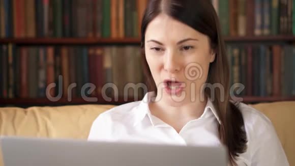 家里的女人带着笔记本电脑使用电脑聊天通过信使应用程序微笑着挥手致意视频的预览图