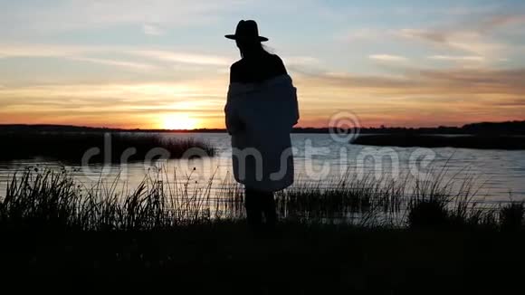 戴着帽子穿着白毛衣的女孩在日落散步视频的预览图