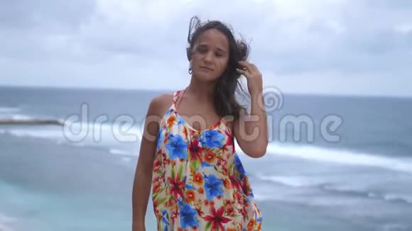 体贴的年轻黑发女人站在海边的岩石上在暴风雨的天气看着镜头慢动作3840x2160视频的预览图
