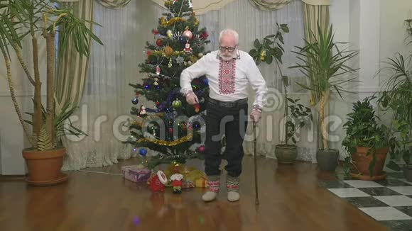 可爱的老人穿着传统的衣服在圣诞树附近缓慢地跳舞视频的预览图