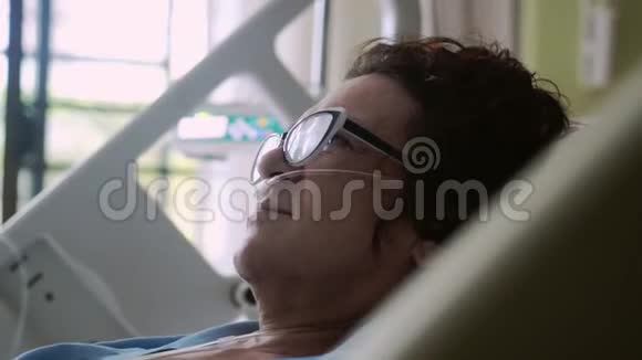 戴眼镜的老年妇女躺在病床上滴着氧气罩心电监护仪的改变视频的预览图