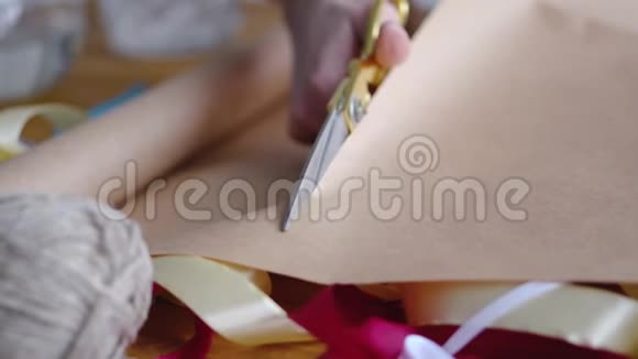 一个女人用剪刀剪纸来包装婚礼生日圣诞节复活节或其他节日的礼物关闭视频的预览图