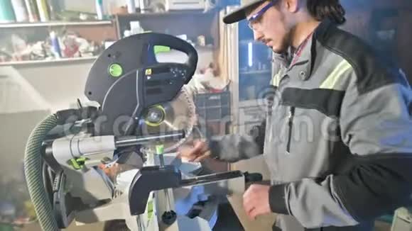一个留着灰色工作服胡须的年轻人一个木匠在家里用一台圆形切割机工作视频的预览图