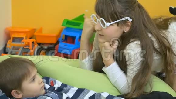 女孩正在用玩具温度计测量一个男孩的体温视频的预览图