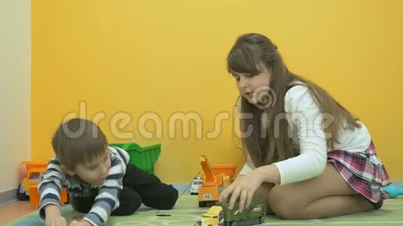 英俊的女孩和小男孩在地板上玩汽车视频的预览图