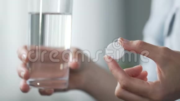 女人拿着一杯水往里面放一片阿司匹林止痛药视频的预览图