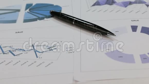 一支黑色钢笔躺在彩色图表上旋转的特写视频的预览图
