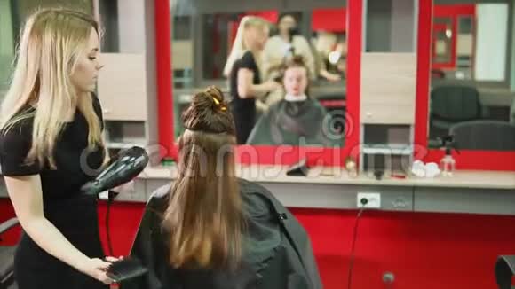 一位发型师用吹风机和梳头把客户的发廊梳起来视频的预览图