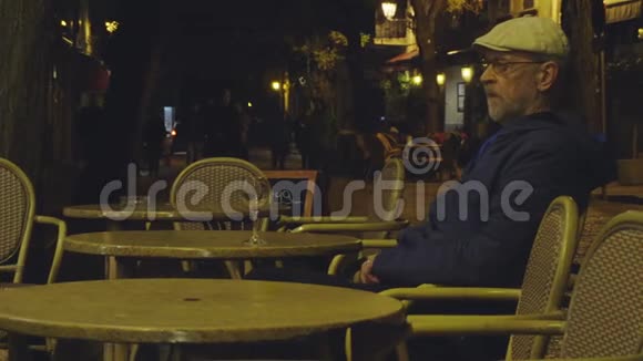 一位老人晚上坐在瓦尔德莫萨村的街头咖啡馆里视频的预览图