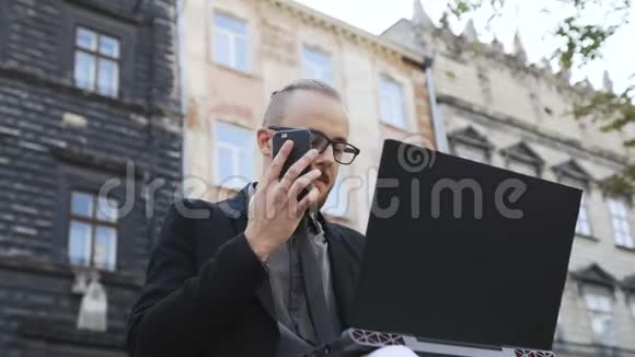 一个戴眼镜的人手里拿着手机在露天的笔记本电脑上奔跑视频的预览图