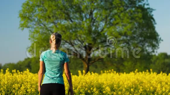 露天健身训练盛开的鲜黄油菜花田背景是一棵大橡树视频的预览图