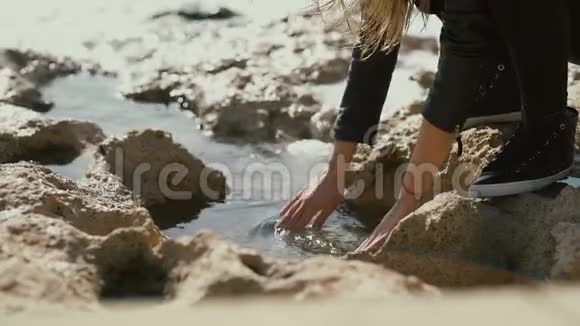 女孩把手伸进海边的水里视频的预览图
