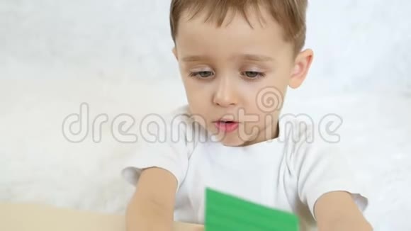 一个孩子正在玩彩色积木坐在白色背景的桌子旁动作缓慢视频的预览图