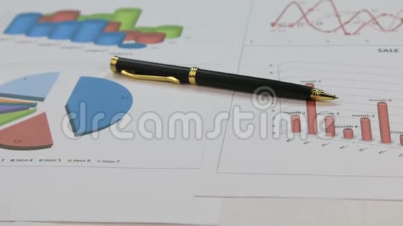 一支金色的笔躺在彩色图表上旋转的特写视频的预览图