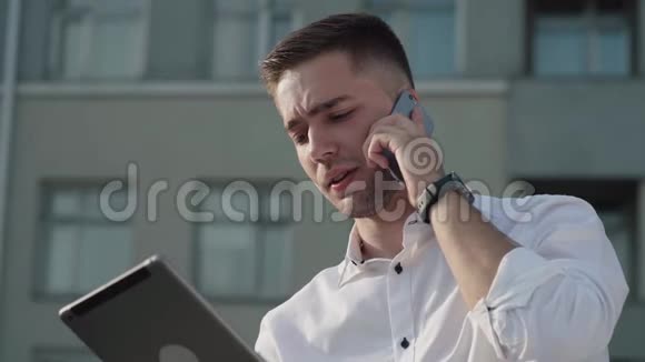 商务人员穿着衬衫一边用平板电脑一边打电话视频的预览图