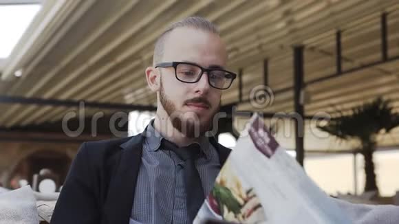 一个戴着胡子眼镜的商人在杂志上视频的预览图