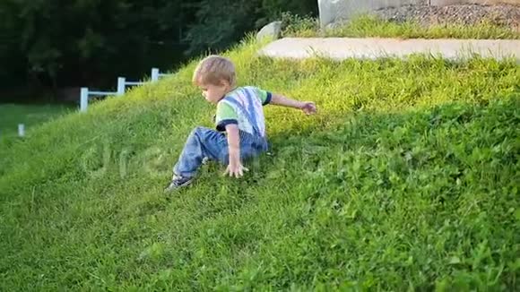 有趣的宝宝在草地上玩从斜坡上滚下来户外乐趣视频的预览图