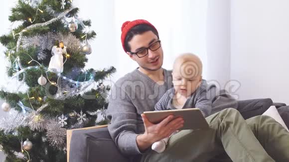 年轻的父亲和小儿子一起玩平板电脑圣诞节视频的预览图