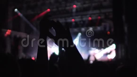 人们在空中挥舞双手在音乐厅欣赏美妙的音乐和灯光表演视频的预览图