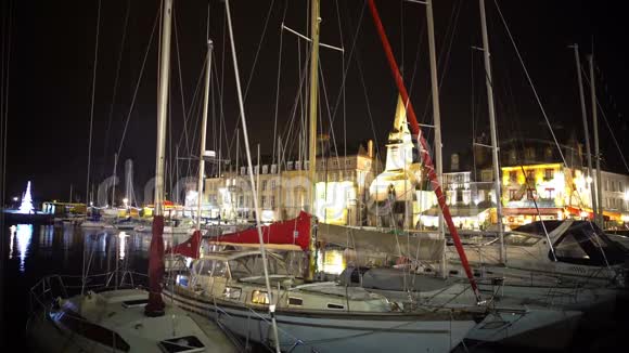 在舒适的小镇度过圣诞节晚上可以看到停泊在港口的游艇和船只视频的预览图