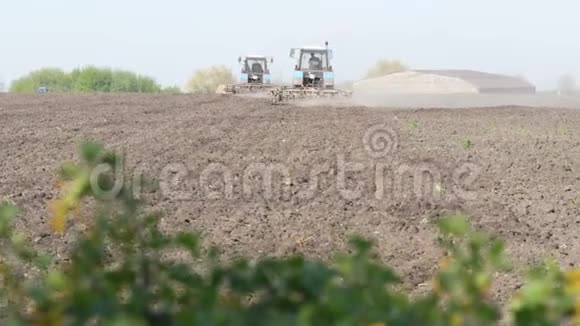早春两台拖拉机在田间工作视频的预览图