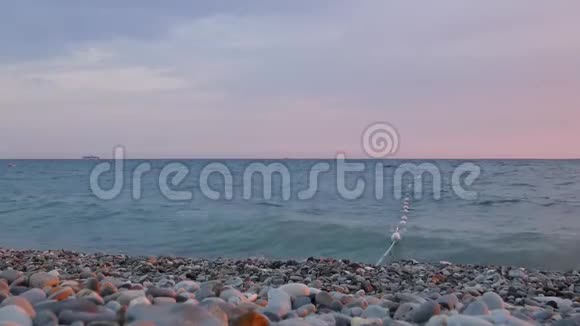 夏天晚上在海边小波浪在灰色的卵石上冲浪视频的预览图