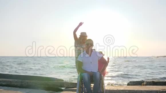 背景海上欢乐的家庭坐轮椅的男人带着小女孩和在户外怀孕的女人与妻子无效视频的预览图