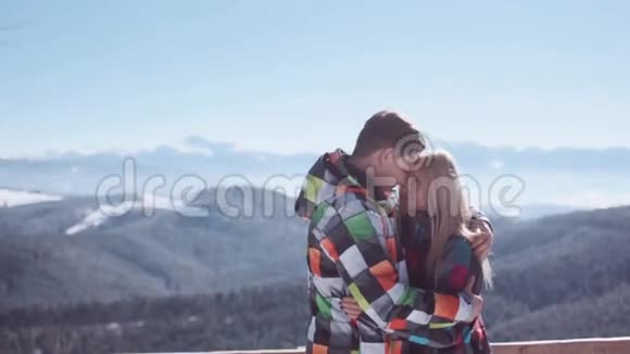 年轻男子温柔地拥抱他迷人的金发女朋友同时站在山上的观景台上令人惊叹视频的预览图