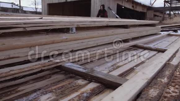 在锯木厂院子里存放的一堆堆积的木板上工作的人视频的预览图