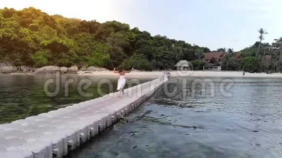 年轻快乐的美丽女子在度假时日落时分在热带岛屿的海上桥上奔跑1920x1080视频的预览图
