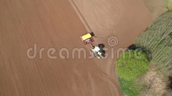 农业拖拉机在林旁春田播种空中视频的预览图