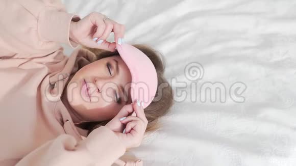 女人在床上戴着睡眠面具漂亮的白种人女人在床上打哈欠女孩在伸展视频的预览图