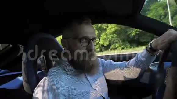 戴眼镜的严肃的小胡子男子坐在方向盘后驾驶跑车视频的预览图