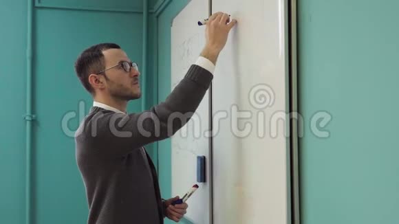 年轻的男讲师在教室的白板上写字视频的预览图