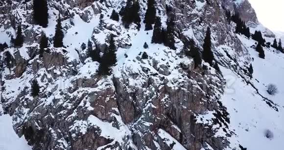 史诗在覆盖着雪的无人机岩石上飞翔陡峭的岩石在山间的雪间视频的预览图
