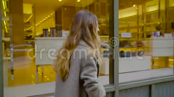 美丽的女人走在靠近精品店的街道上视频的预览图