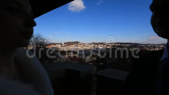 在城市全景的背景下一对幸福的新婚夫妇在阳台上温柔地接吻搬迁视频的预览图