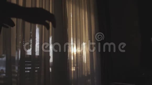 年轻漂亮的女孩打开门窗帘穿过阳光走到露台上享受着阳光下的时刻视频的预览图