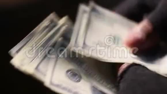戴着破旧的无指手套数着美元现金的男手特写镜头视频的预览图