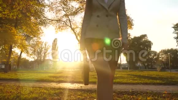 穿裙子的女商人穿着美丽的日落带着黑色公文包在公园里散步美丽的腿视频的预览图