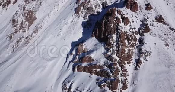 史诗在覆盖着雪的无人机岩石上飞翔陡峭的岩石在山间的雪间视频的预览图
