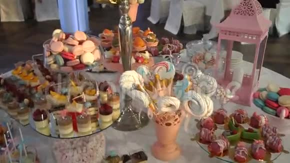 在婚礼上偷拍了糖果棒桌子上摆满了各种五颜六色的糖果蛋糕蛋糕马卡龙和视频的预览图