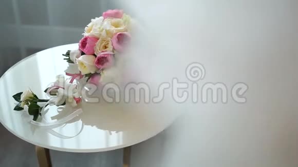 美丽的婚礼花束粉红色和白色的玫瑰和可爱的五颜六色的布托尼躺在白色的桌子上视频的预览图
