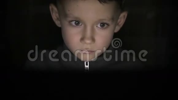 那个男孩坐在黑暗中看着电脑视频的预览图